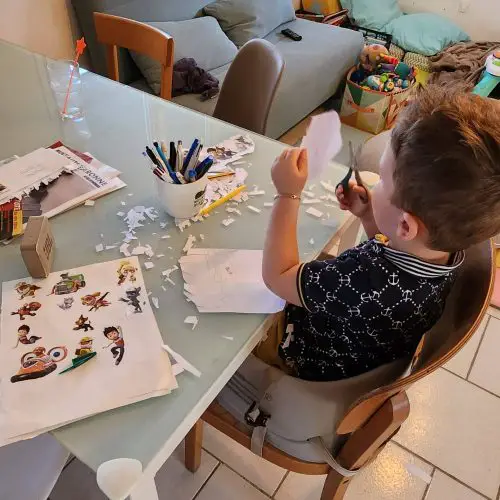 Enfant en train de découper du papier à une table d'activités
